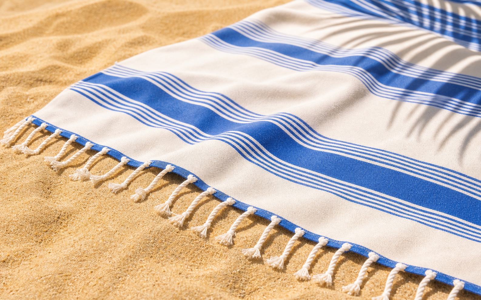 Pestemal spread on warm sand with sun shadow